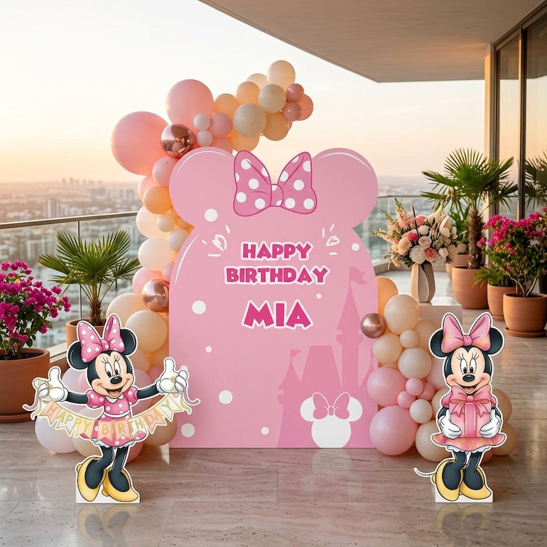 Puede incluir: Decoraci&oacute;n de fiesta de cumplea&ntilde;os con tem&aacute;tica de Minnie Mouse. Presenta un gran recorte rosa con el texto "Happy Birthday Mia" y orejas de Minnie. Globos en tonos rosa y melocot&oacute;n, y recortes de Minnie Mouse completan la escena.