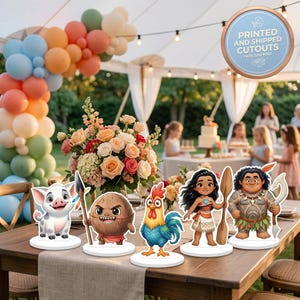 Puede incluir: Cinco figuras recortadas que representan un cerdo, una criatura coco, un gallo, una chica con un remo y un hombre con un gancho, sobre bases circulares blancas. Las figuras est&aacute;n sobre una mesa de madera con un centro de flores y globos.