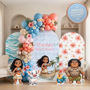 May include: A party backdrop set featuring three arched panels with Moana-themed graphics, including a central panel with the text Emma's Ocean Dream, a balloon garland in blue, peach, and tan, and four character cutouts of Moana, Pua, Heihei, and Maui.