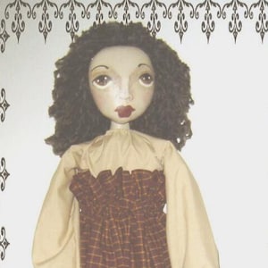 Puede incluir: Una muñeca de tela con cabello oscuro rizado, ojos grandes de color marrón y labios rojos. La muñeca viste una blusa beige de manga larga con cuello con volantes y una falda de cuadros marrones y amarillos. Tiene piernas blancas y zapatos negros.