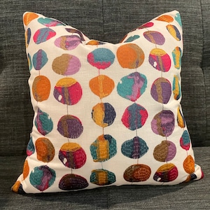 May include: A white throw pillow with a colorful abstract pattern of circles in shades of orange, purple, teal, and brown. The circles are connected by thin lines.