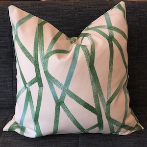 May include: A white pillow with a green geometric pattern. The pattern is made up of thick, brushstroke-like lines that create a modern and abstract design.
