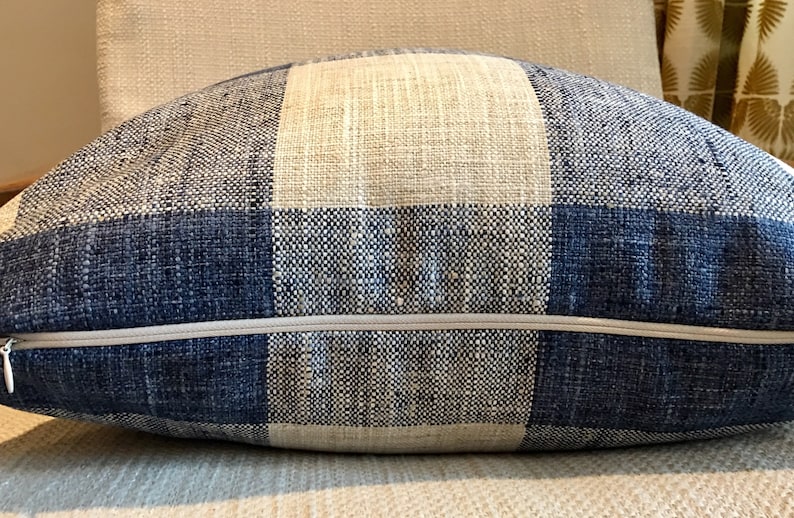 Puede incluir: Una almohada de tiro a cuadros azules y blancos con cierre de cremallera.