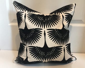 May include: Square decorative pillow with a repeating pattern of black crane silhouettes against a white background. The pillow has a soft, textured appearance and is likely made of fabric. The design is symmetrical and modern.