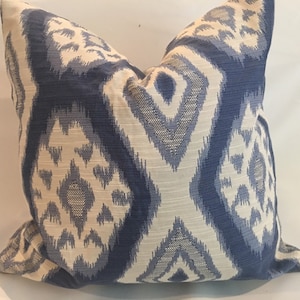 May include: A blue and white patterned throw pillow with a geometric design. The pillow is made of a soft, textured fabric.