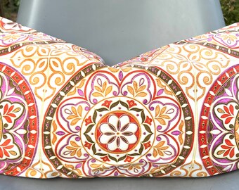May include: A white pillow with a colorful mandala pattern in shades of orange, red, purple, and brown. The pillow is decorated with intricate details and a floral design.