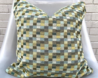 Puede incluir: Una almohada de tiro de cuadros verdes, amarillos y azules con textura tejida.