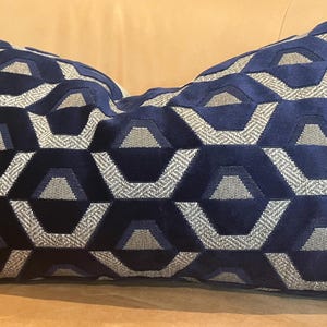 May include: A blue and silver geometric patterned throw pillow. The pillow is made of a soft, plush fabric and features a repeating pattern of hexagons.
