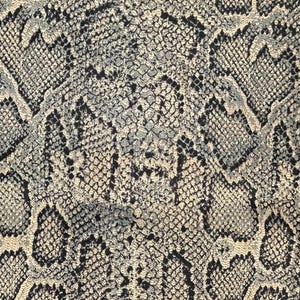 May include: A close-up of a snakeskin pattern fabric with a beige and black color scheme. The fabric has a textured surface and a repeating pattern of scales.