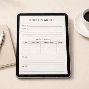 Peut inclure: Une tablette numérique affichant une mise en page "Study Planner" avec des sections pour les objectifs et un emploi du temps d'étude. Un stylo blanc et un bloc-notes sont à gauche, et une tasse de café sur une soucoupe à droite. La tablette a un bord noir.
