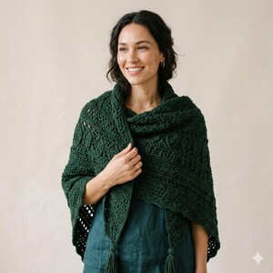May include: A dark green crocheted shawl with a textured pattern and tassels. The shawl is draped over the shoulders, showcasing the intricate stitchwork and the rich colour. The shawl is a cosy accessory.