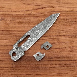 May include: A white ceramic mug with a black handle and the text "But First, Coffee" in a black, handwritten-style font. The mug is on a white surface.