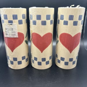 May include: Three cylindrical rolls of decorative paper. Each roll features a cream-colored background with a pattern of blue checkered squares and a large red heart. The rolls are wrapped in clear plastic. The tag reads "MADE IN U.S.A."