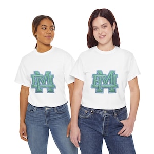 Könnte beinhalten: Zwei weiße T-Shirts mit einem grün-blauen, gestickten "M"-Logo. Die Shirts werden mit blauen Jeans getragen. Das Bild zeigt zwei Personen, eine mit dunklem Haar und die andere mit hellem Haar, beide lächeln.