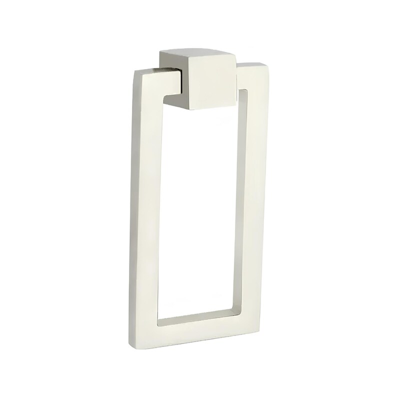 Puede incluir: Un tirador de armario rectangular blanco roto con una parte superior cuadrada y un asa rectangular. El asa es abierta en el centro. El herraje es de metal y est&aacute; dise&ntilde;ado para muebles.
