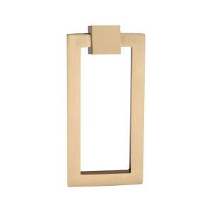 Puede incluir: Un tirador de armario rectangular de color dorado con un detalle cuadrado en la parte superior. El tirador tiene un dise&ntilde;o sencillo y moderno, con un asa rectangular y una placa de montaje cuadrada. La ferreter&iacute;a es de metal y tiene un acabado cepillado.