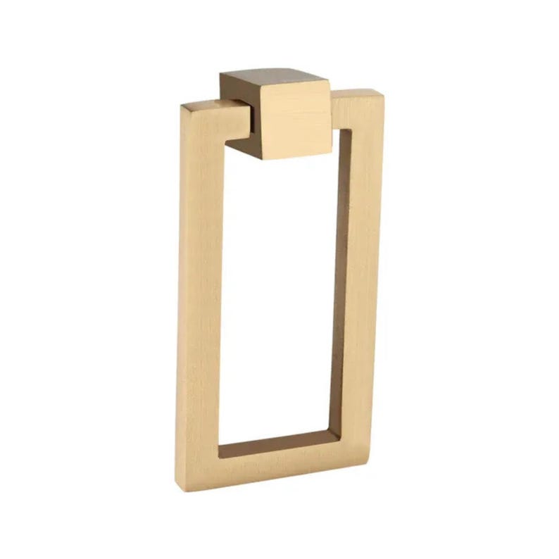 Puede incluir: Un tirador de armario rectangular de color dorado con una parte superior cuadrada. El tirador tiene un dise&ntilde;o simple y moderno, perfecto para a&ntilde;adir un toque de elegancia a los muebles. El herraje es de metal y tiene un acabado cepillado.