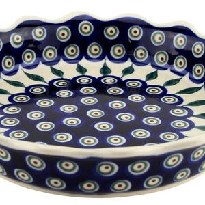 May include: A ceramic serving bowl with a scalloped edge. The bowl features a dark blue background with a repeating pattern of white, green, and red circles. The rim is white.