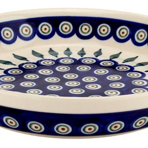 May include: A round, ceramic serving dish with a white interior and a dark blue rim and base. The dish is decorated with a repeating pattern of blue, red, and green circles. The center of the dish features a similar pattern.