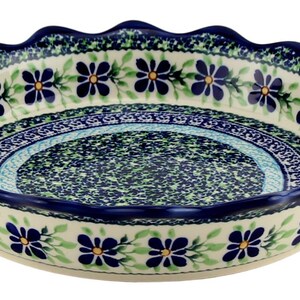 May include: Ceramic pie dish with a scalloped edge, featuring a floral pattern in blue, green, and yellow. The rim and base are dark blue, and the interior has a speckled design. A decorative serving dish for baking and serving.