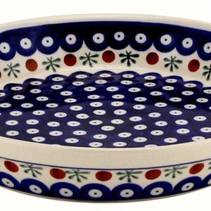 May include: A round, ceramic serving dish with a blue and white floral pattern. The dish has a white rim and a dark blue interior with white polka dots. The rim features a scalloped design with blue, red, and green accents. This decorative dish is perfect for serving food.