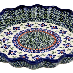 May include: A ceramic pie dish with a scalloped edge. The dish features a white interior with a floral pattern in blue, green, and orange. The rim and edge are dark blue.