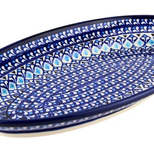 May include: An oval ceramic serving platter with a blue and white floral pattern. The rim is dark blue, and the interior features a repeating design of blue and white elements. The platter is ideal for serving food.