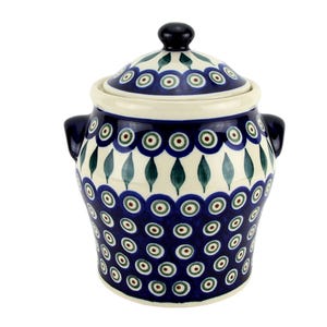 May include: A ceramic jar with a lid and two side handles, featuring a cream-colored base decorated with a repeating pattern of dark blue circles with green and brown centers, interspersed with green leaf-like shapes around the upper section.