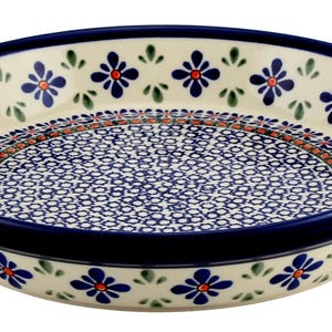 May include: A round ceramic serving dish with a dark blue rim and a cream-colored interior. The dish is decorated with blue floral patterns and a detailed blue and red design in the center. A decorative piece for the kitchen.