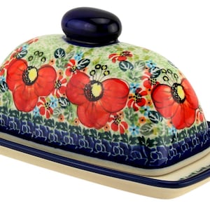 May include: A ceramic butter dish with a domed lid and rectangular base. The lid is decorated with red poppy flowers and green foliage on a light green background. The base and rim are dark blue.