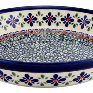 May include: A round ceramic serving dish with a blue rim and floral pattern. The dish features a cream-colored base with a repeating pattern of blue flowers with orange centers and green leaves. The interior has a blue and white dotted design.