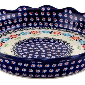 May include: A round, ceramic pie dish with a scalloped edge. The dish features a dark blue background with a repeating pattern of small red and white flowers. The interior has a floral design with red, blue, and green accents.