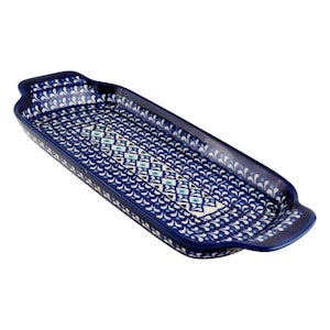 May include: A rectangular ceramic serving tray with integrated handles on both ends. The surface features a dense pattern of dark blue, light blue, and white floral motifs, with a central band of geometric diamond shapes and small blue dots.