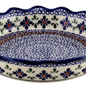 May include: A round ceramic pie dish with a scalloped edge. The dish features a blue and white floral pattern with orange accents. The rim and base are a deep blue, and the interior has a detailed blue and white design.