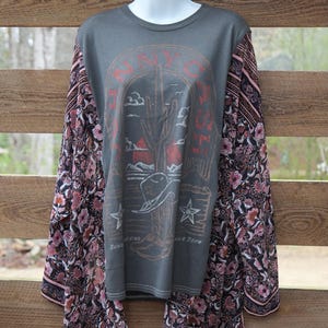 May include: Gray long-sleeve shirt with a graphic of a cactus, cowboy hat, and stars. The sleeves are patterned with a floral design in shades of pink, black, and white. The shirt has the text "SAVOY" and "SUN GOING DOWN".