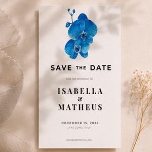 Pode incluir: Cartão de convite de casamento com um design de orquídea azul. O texto diz "SAVE THE DATE" seguido dos nomes Isabella & Matheus, e a data do casamento, 15 de novembro de 2026, em Como, Itália.