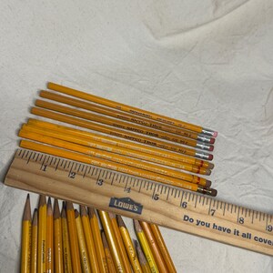 May include: A collection of yellow pencils with erasers, some labeled "BONDAD NAPTICO THOR" and "DIXON TICONDEROGA", alongside a wooden ruler. The ruler has the text "Do you have it all covered?" and the Lowe's logo.