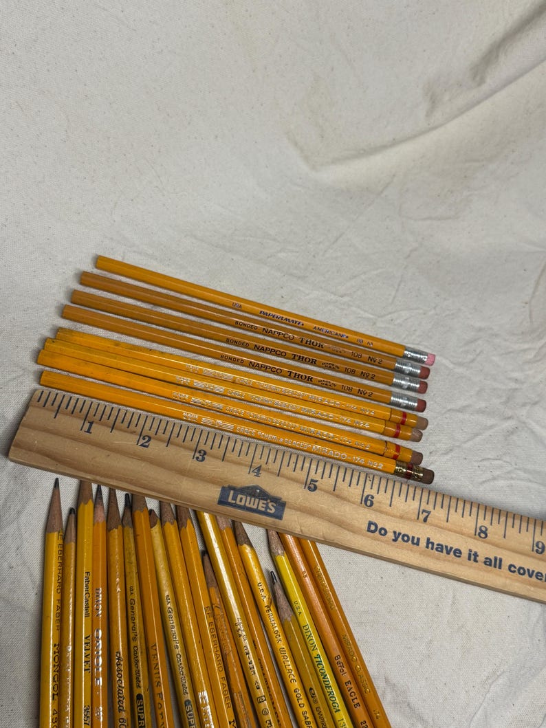 May include: A collection of yellow pencils with erasers, some labeled "BONDAD NAPTICO THOR" and "DIXON TICONDEROGA", alongside a wooden ruler. The ruler has the text "Do you have it all covered?" and the Lowe's logo.