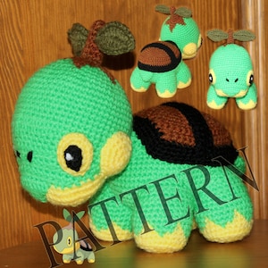 May include: A green and brown crocheted turtle amigurumi toy with a leafy stem on its head. The toy is sitting on a wooden surface.