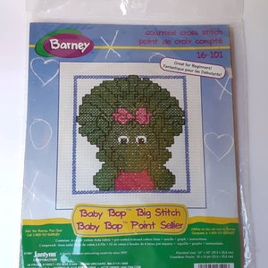 May include: A counted cross stitch kit featuring Baby Bop from the Barney & Friends television show. The kit includes 6-count Aida fabric, pre-sorted 6-strand cotton floss, a needle, a graph, and instructions. The finished size is 10 inches by 10 inches.