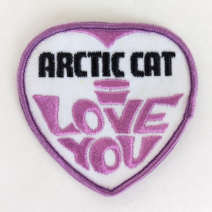 May include: Heart-shaped patch with a white center and a purple border. The patch features the words "ARCTIC CAT" in black and "LOVE YOU" in purple, with a stylized design.