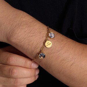May include: Gold-colored charm bracelet with three circular pendants. Two pendants feature small photos, and the central pendant is engraved with the name "Jack" and the date "05.06.2023". The bracelet is worn on a wrist.