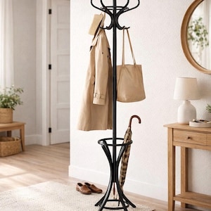 Puede incluir: Perchero de metal negro con múltiples ganchos para colgar abrigos, sombreros y bolsos. Una gabardina beige, un bolso tote y un sombrero de paja cuelgan de los ganchos. Un paraguas descansa en la base y unos zapatos marrones están en el suelo.