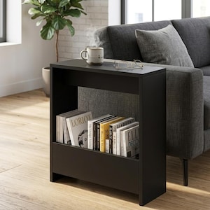 May include: A black side table with a built-in shelf, holding several books. A mug of coffee and eyeglasses rest on the tabletop. The table is next to a gray sofa and a window, with a plant in the background.