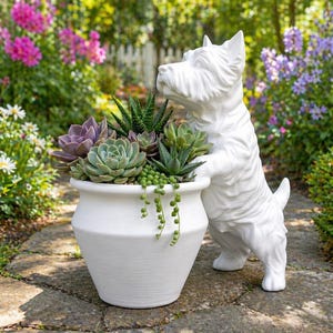 May include: A white ceramic dog statue supports a white planter filled with succulents. The planter contains a variety of green and purple succulents, including a trailing string of pearls plant. The scene is set outdoors with a stone path and a garden backdrop.