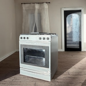 Peut inclure: Une cuisinière miniature blanche avec une porte de four en verre noir, six boutons de commande noirs sur le panneau avant et une surface de cuisson noire. L'appareil présente une finition texturée pour une maison de poupée.