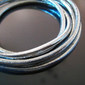 May include: Silver metallic cord, coiled and twisted, with a shiny, reflective surface.
