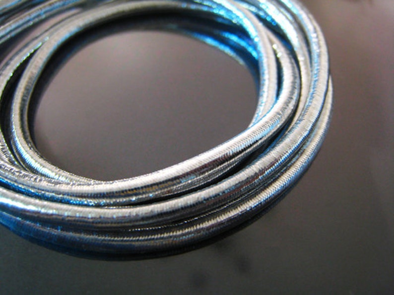 May include: Silver metallic cord, coiled and twisted, with a shiny, reflective surface.
