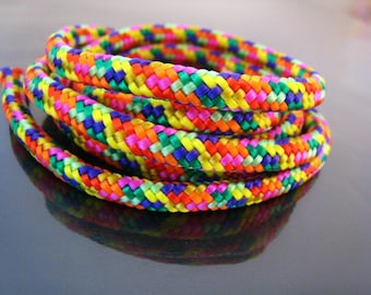 May include: A multi-coloured braided rope with a rainbow pattern. The rope is made of a thick, durable material and is ideal for crafting or decorating.