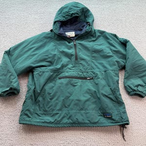 May include: A dark green L.L.Bean hooded pullover jacket featuring a half-zip front closure, a large horizontal zippered front pocket, long sleeves with elastic cuffs, and an adjustable drawstring hem with a dark blue interior lining.